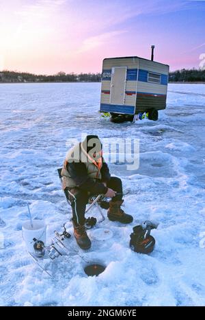 Un homme dédié à la pêche sur glace sur un lac gelé du Minnesota. Banque D'Images