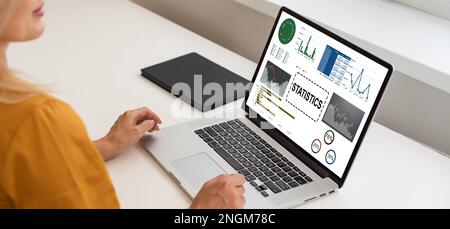 Analyste féminine à son bureau travaille sur un ordinateur portable montrant des statistiques, des graphiques et des graphiques. Elle travaille sur la table en bois dans le bureau de création. Au-dessus de Banque D'Images