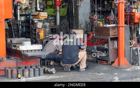 SAMUT PRAKAN, THAÏLANDE, 04 2023 FÉVRIER, des hommes travaillent dans un atelier dans la rue Banque D'Images