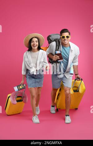 Couple de touristes avec des billets, passeports et valises sur fond rose Banque D'Images