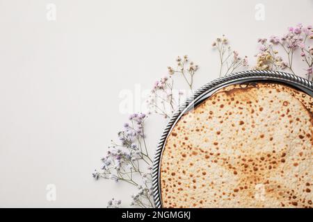 Savoureux matzos et fleurs de gitsophila fraîches sur fond gris clair, plat avec espace pour le texte. Fête de la Pâque (Pesach) Banque D'Images
