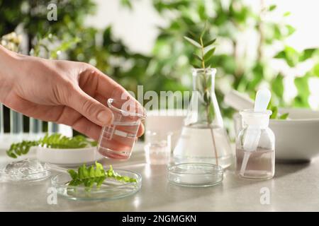 Scientifique faisant des produits cosmétiques à la table grise, gros plan Banque D'Images