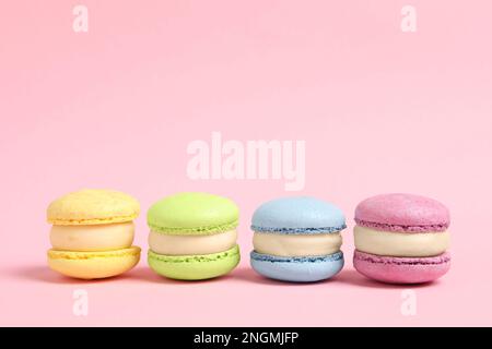 Délicieux macarons colorés sur fond rose, espace pour le texte Banque D'Images