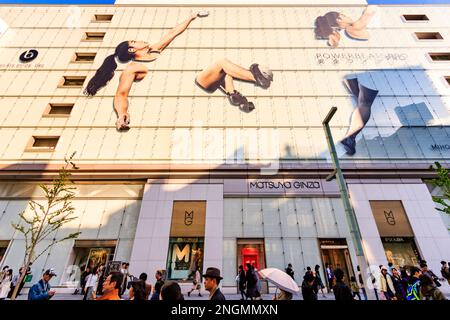 Sur la chaussée, regardant le magasin Matsuya Ginza avec sa façade en verre vert avec Écouteurs powerbeats pro display. Heure d'or. Banque D'Images