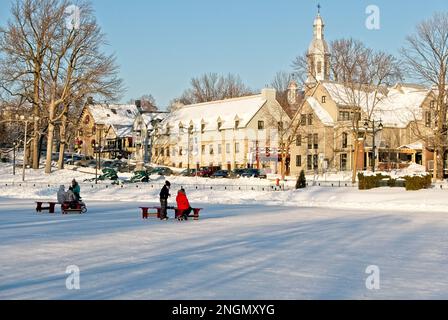 Jeunes qui patientent sur l'étang des Moulins gelé journé ensoleillé hiver. Les enfants patinent sur un étang gelé à Terrebonne par temps ensoleillé. Banque D'Images