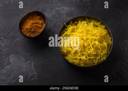 Choucroute maison à l'ail, à l'oignon et au curcuma sur fond texturé foncé. aliments fermentés sains, probiotiques naturels, aliments végétaliens. vue de dessus Banque D'Images