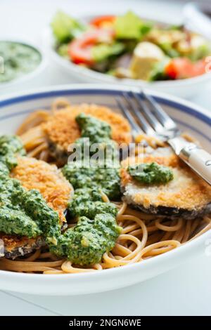 Plat avec aubergines panées maison et pesto aux épinards, servi sur spaghetti. Banque D'Images