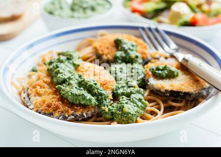 Plat avec aubergines panées maison et pesto aux épinards, servi sur spaghetti. Banque D'Images