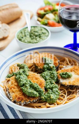 Plat avec aubergines panées maison et pesto aux épinards, servi sur spaghetti. Banque D'Images