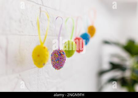 Oeufs de Pâques accrochés sur la corde à linge isolée sur blanc Banque D'Images