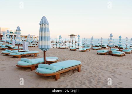 Transats et parasols vides sur une plage de sable près de la mer Banque D'Images