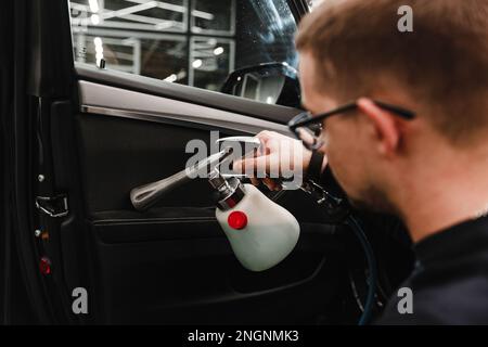 Un homme nettoie une voiture et sèche l'intérieur avec un outil de polissage nettoyage manuel de voiture. Conception de voiture et de lavage de voiture. Banque D'Images