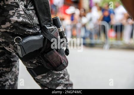 Un policier tient une arme dans un étui. Lors d'un événement de masse. République dominicaine. Banque D'Images