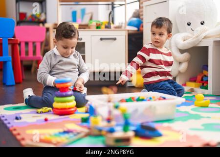 Deux enfants jouent avec des jouets assis sur le sol à la maternelle Banque D'Images