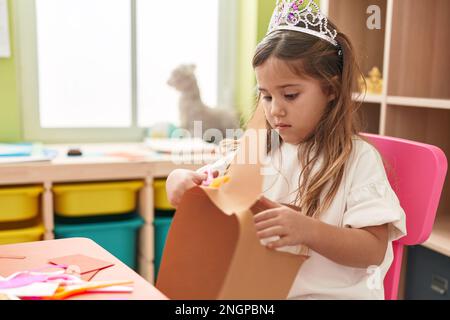 Adorable fille blonde étudiante portant le papier de coupe de la couronne de princesse à la maternelle Banque D'Images