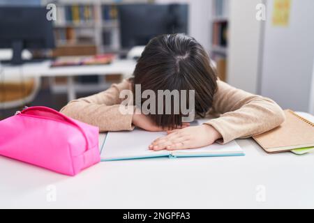 Adorable étudiante hispanique de fille a souligné se pencher sur le livre en classe Banque D'Images