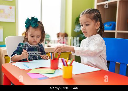 Frère et soeur élèves assis sur table de dessin sur papier à la maternelle Banque D'Images