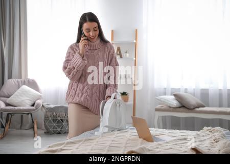 Jeune femme avec smartphone et sac à dos dans la chambre. Routine du matin Banque D'Images