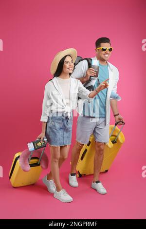 Couple de touristes avec des billets, passeports et valises sur fond rose Banque D'Images