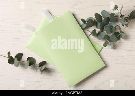 Sachets parfumés et branches d'eucalyptus sur table en bois blanc, plat Banque D'Images