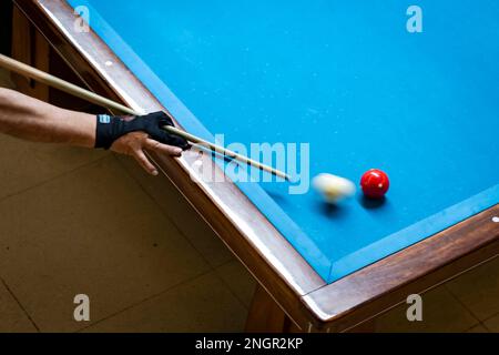 Bras du joueur tenant le repère au-dessus de la table de billard. Le joueur vient de frapper la balle blanche. Banque D'Images