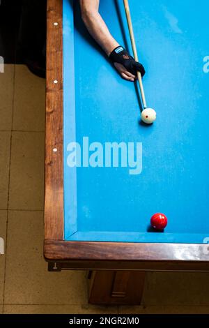 Bras du joueur tenant le repère au-dessus de la table de billard. Le joueur est sur le point de frapper la balle blanche. Banque D'Images