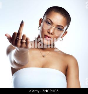 Vivre la vie sans s'excuser. Photo studio d'une belle jeune femme montrant le doigt du milieu sur un fond gris. Banque D'Images