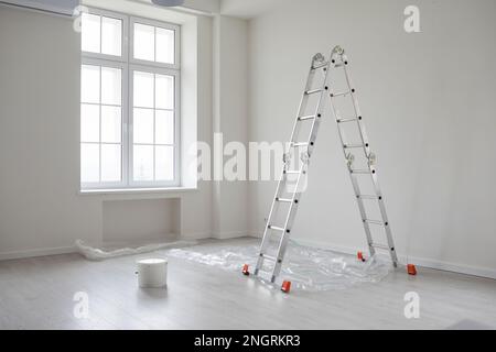Intérieur moderne et vide de la salle de séjour avec murs peints en blanc, échelle et un seau de peinture Banque D'Images