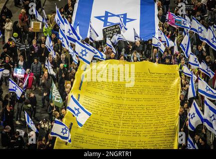 Tel Aviv, Israël. 18th févr. 2023. Les manifestants marchent avec la copie de la déclaration d'indépendance d'Israël et les drapeaux pendant la manifestation. Les gens ont protesté à tel Aviv contre le gouvernement de droite du Premier ministre Benjamin Netanyahu et contre sa réforme juridique controversée. La réforme juridique proposée permettrait au Parlement de renverser la décision de la Cour suprême par un vote à la majorité parmi les législateurs de 120 sièges. Toutefois, ils nomment des juges, qui renforcent leur influence politique sur le système. Crédit : SOPA Images Limited/Alamy Live News Banque D'Images