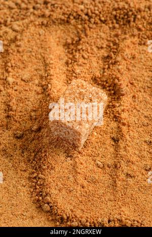 un cube de sucre brun sur du sucre granulé. Photo de haute qualité Banque D'Images