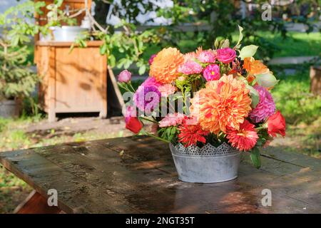 Roses, asters, dahlia en vase dans le jardin sur une table en bois. Journée ensoleillée dans le village. Véranda dans le jardin. Banque D'Images