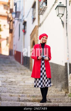 Femme de voyage élégante debout sur les escaliers en ville et souriante Banque D'Images