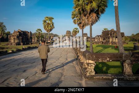 Un homme local marche le long de la chaussée en direction de la porte ouest au célèbre temple antique d'Angkor Wat au Cambodge. Banque D'Images