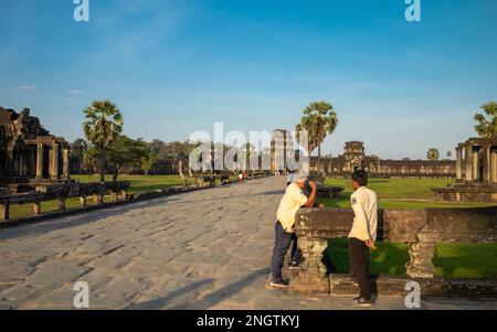 Deux guides touristiques officiels discutent sur la chaussée de la porte Ouest au célèbre temple antique d'Angkor Wat au Cambodge Banque D'Images