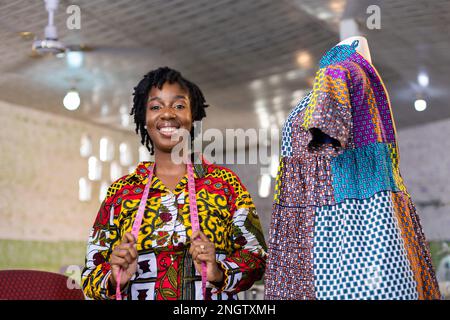 Couturière africaine à succès Entreuner debout par sa robe africaine colorée à motif d'impression avec ruban de mesure autour de son cou. Banque D'Images