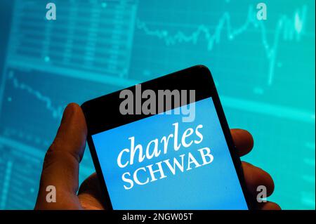 Dans cette illustration, le logo de la société multinationale américaine de services financiers Charles Schwab est affiché sur un smartphone avec un graphique d'indice boursier économique en arrière-plan. Banque D'Images