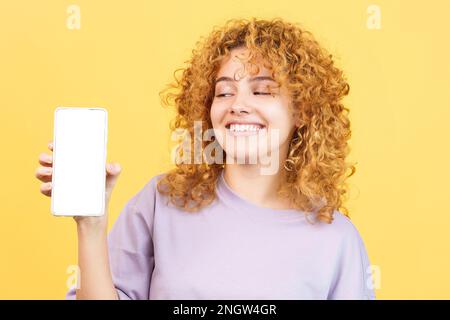 Femme souriante montrant l'écran vide du mobile Banque D'Images