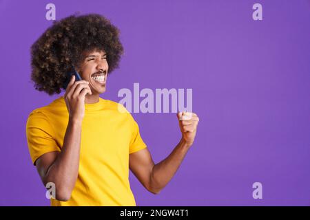 Joyeux homme africain en train de célébrer tout en emportant sur le mobile Banque D'Images