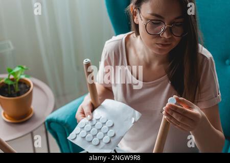 Une femme fixe un tampon de feutre sur la jambe de la chaise, en se souciant du sol Banque D'Images