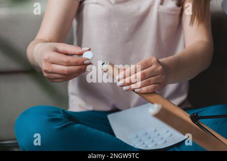 Une femme fixe un tampon de feutre sur la jambe de la chaise, en se souciant du sol Banque D'Images