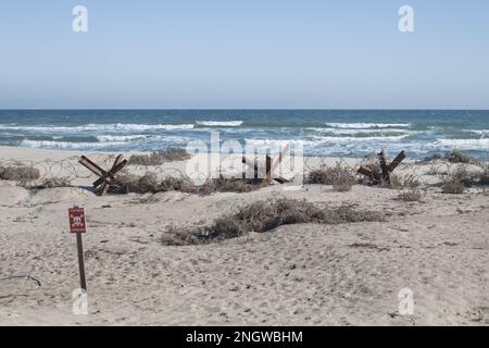 Hérissons anti-chars, barbelés sur la plage au bord de la mer (l'inscription sur la plaque se traduit par - arrêt - mines) Banque D'Images