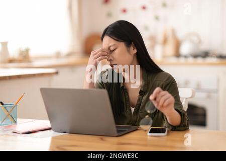Femme asiatique surtravaillée indépendante assise devant un ordinateur portable Banque D'Images