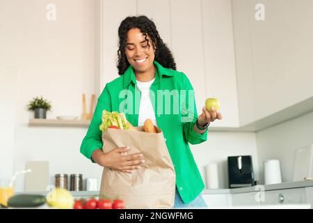 Black Lady Déballage du sac d'épicerie en papier après avoir fait ses courses dans la cuisine Banque D'Images