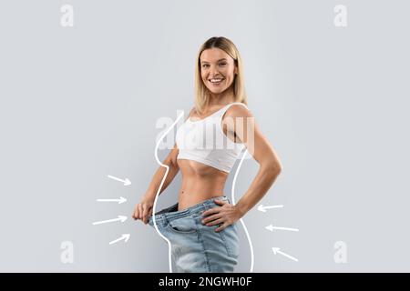 Bonne dame blonde en Jean, montrant ample à la taille Banque D'Images