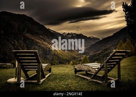 Transats sur un pré de montagne avec forêt de montagne automnale et ciel nuageux menaçant, vallée de Martell, Merano, Vinschgau, Tyrol du Sud, Italie Banque D'Images