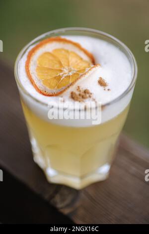 De la levure fraîche de gin de cochon avec tonique et jus. Décoré d'une tranche d'orande séchée et de poudre de cannelle. Table en bois Banque D'Images