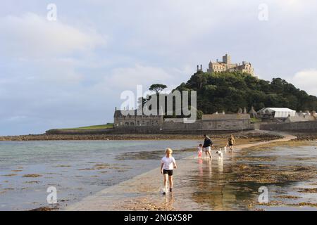 Famille touristique marchant le long de la promenade légèrement couverte loin de St Michael monte à l'arrivée des marées Banque D'Images