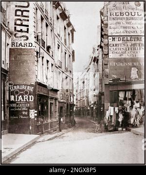 Vintage 1800s Paris rue de Bievre (du boul. [Boulevard] St. Germain) entrée de la petite rue sinueuse, magasin de vêtements avec articles de rechange sur le chemin de droite. Rue de Bièvre, Paris, France. Date vers 1853 – 70 impression d'argent par le photographe Charles Marville Banque D'Images