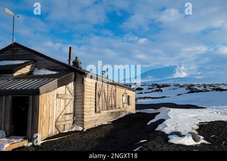 Antarctique, mer de Ross, île de Ross, Cap Evans. Vue extérieure de la cabane historique de Scott avec le mont Erebus au loin. Banque D'Images