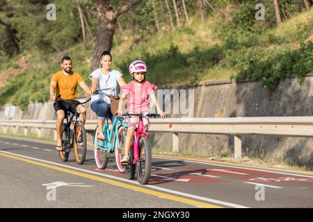 Mère, père et fille enfant s'amuser en vacances à vélo près de la mer. Promenade en vélo en famille sur la côte. Banque D'Images